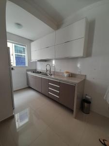 uma cozinha com armários brancos e um lavatório em Apto novo com piscina e pátio na praia dos Ingleses em Florianópolis