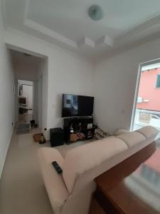 uma sala de estar com um sofá e uma televisão em Apto novo com piscina e pátio na praia dos Ingleses em Florianópolis