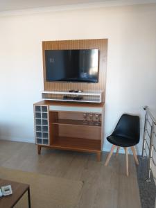 a living room with a television on a wooden entertainment center at COBERTURA no CENTRO BOMBINHAS in Bombinhas