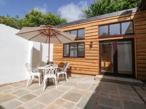 un patio con sombrilla, mesa y sillas en Finest Retreats - Hillfarrow Hideaway en Tiverton