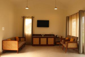 een woonkamer met een bank en een tv bij The Bageecha in Vrindāvan