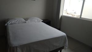 - un lit blanc avec deux oreillers dans une chambre dotée d'une fenêtre dans l'établissement Casa Elegante, Cómoda y Relax, à Santa Cruz de la Sierra