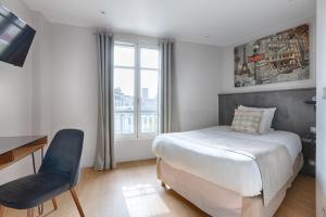 sypialnia z łóżkiem, biurkiem i oknem w obiekcie Hotel de France Invalides w Paryżu
