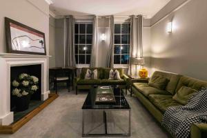 a living room with a green couch and a fireplace at Shared Guest House 5 mins walk from Vauxhall and Nine Elms Station with off-site parking near US embassy in London