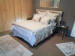 1 dormitorio con 1 cama con sábanas y almohadas blancas en Green Hills Farm House, en Drummond