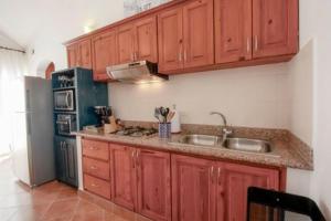 uma cozinha com armários de madeira, um lavatório e um frigorífico em Beach Apartment em Punta Cana