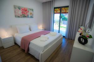 um quarto com uma cama branca e um vaso de flores em Villa Rosa em Porto Moniz