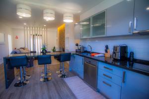 uma cozinha com armários azuis e bancos de bar azuis em Villa Rosa em Porto Moniz
