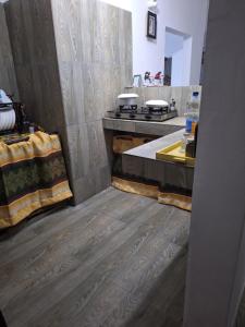 cocina con suelo de madera, encimera y fregadero en La CASETTA A ZANZIBAR B&B, en Uroa