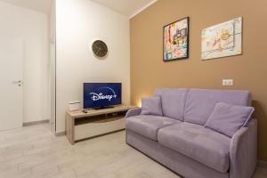 a living room with a purple couch and a tv at Crescenzago#34, vicino Metro M2 e Ospedale San Raffaele in Milan