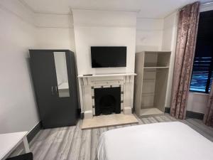 a bedroom with a bed and a tv on a fireplace at Rooms in Modernised Victorian House in Croydon
