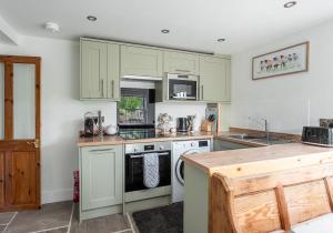 a kitchen with green cabinets and a stove top oven at A D Coach House Cottage in Richmond