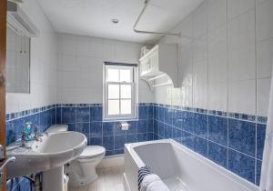 a blue and white bathroom with a tub and a sink at A D Coach House Cottage in Richmond +34 photos
