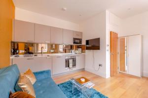 a living room with a blue couch and a kitchen at Central & Cosy 1BD Flat - Soho in London