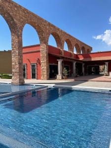 a swimming pool in front of a building with arches at Casa las Alas de San Miguel in San Miguel de Allende