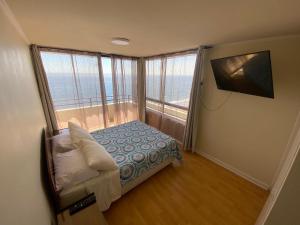 a small bedroom with a bed and a large window at Deptos y habitaciones en sector sur de Iquique, Chile, frente al mar in Iquique