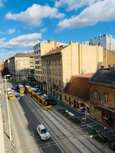 Margaret Boulevard Apartment - with balcony في بودابست: شارع المدينة فيه باصات وسيارات ومباني