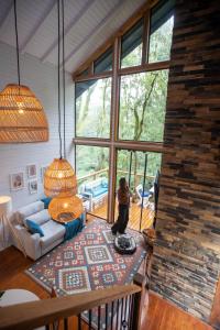 a person standing in a living room with a large window at Cabana Gato do Mato in São Francisco de Paula