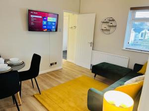 a living room with a couch and a tv on the wall at Stylish Central Apartment in Cardiff
