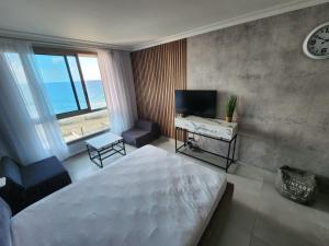 een slaapkamer met een bed, een televisie en een bureau bij maytoro in Haifa