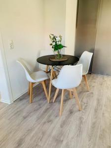 a dining room table with white chairs and a vase with flowers at Blaue 8 in Rampe