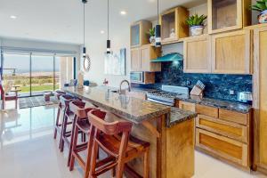 a kitchen with wooden cabinets and a large island with bar stools at Tramonti Condo Tari #107 in Cabo San Lucas