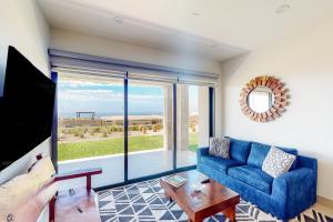 un soggiorno con divano blu e una grande finestra di Tramonti Condo Tari #107 a Cabo San Lucas