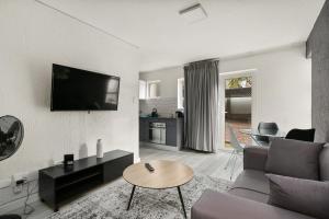 a living room with a couch and a tv on a wall at Marley on Katherine Apartments in Johannesburg