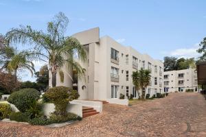 un edificio blanco con palmeras delante en Marley on Katherine Apartments, en Johannesburgo