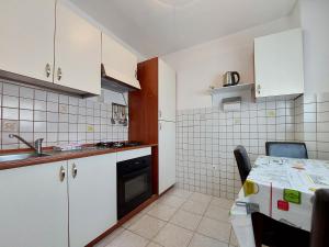 a small kitchen with white cabinets and a table at Apartments Marija in Selce