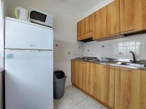 a white refrigerator in a kitchen with wooden cabinets at Apartments Marija in Selce
