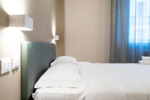 ein weißes Bett in einem Zimmer mit Fenster in der Unterkunft Astoria Comfort Rooms in Bologna