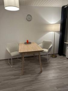 Zimmer mit einem Tisch, 2 Stühlen und einer Uhr in der Unterkunft Ferienwohnung zur Sternblume in Bruchweiler-Bärenbach