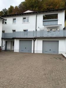 ein weißes Gebäude mit vier Garagentüren und einem Balkon in der Unterkunft Ferienwohnung zur Sternblume in Bruchweiler-Bärenbach