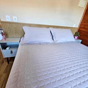 - un grand lit blanc dans une chambre avec une table dans l'établissement Pousada Morada dos Sonhos, à Urubici