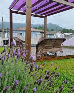 a bench sitting under a pergola on a deck with purple flowers at Pousada Morada dos Sonhos in Urubici
