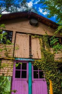 una casa con una puerta rosa y ventanas en Refugio del Bosque en El Bolsón