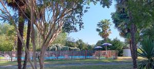 un parc avec une clôture, une piscine et des arbres dans l'établissement Le Moulin du Comte, à Bourrouillan