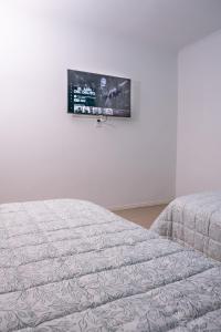 - une chambre avec un lit et une télévision murale dans l'établissement Alta Pinta, à Paso de los Libres