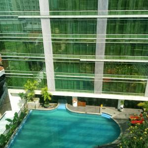 - une vue sur la piscine en face d'un grand bâtiment dans l'établissement Vins Room at Mataram City Tower Sadewa, à Kejayan