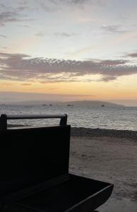 un banco sentado en la playa cerca del océano en Chalets Paracas, en Paracas