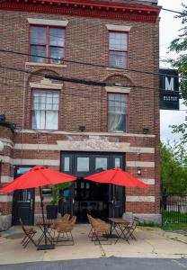 two tables and chairs with red umbrellas in front of a building at Michie Hostel in Providence