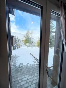 przesuwane szklane drzwi z widokiem na pokryty śniegiem dziedziniec w obiekcie Studio 2 Alpes 1800, pied des pistes w mieście Les Deux Alpes