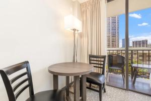 a room with a table and chairs and a balcony at Spacious & Sophisticated Palms Studio condo in Honolulu