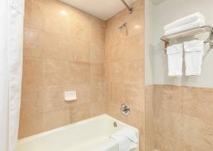 a bathroom with a tub and a shower with towels at Spacious & Sophisticated Palms Studio condo in Honolulu