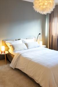 ein Schlafzimmer mit einem großen weißen Bett und einem Kronleuchter in der Unterkunft namastay! - Moderne Stadtwohnung am NTM und Blick auf den Wasserturm in Mannheim