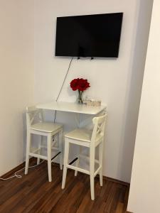 mesa blanca con 2 sillas y TV en la pared en Cozy Homestay at Andel Prague, en Praga