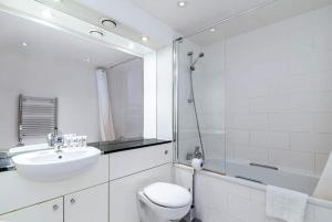 een badkamer met een wastafel, een toilet en een douche bij Austin David Apartments ExCeL in Londen