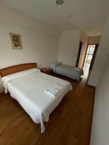 a bedroom with a white bed and a chair at Casa Diocesana VIA LUCIS in Santiago de Compostela