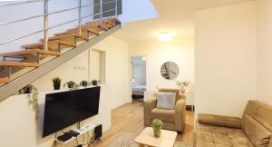 ein Wohnzimmer mit einem TV und einer Treppe in der Unterkunft FilinHome Papa Suite 2 in Novi Sad